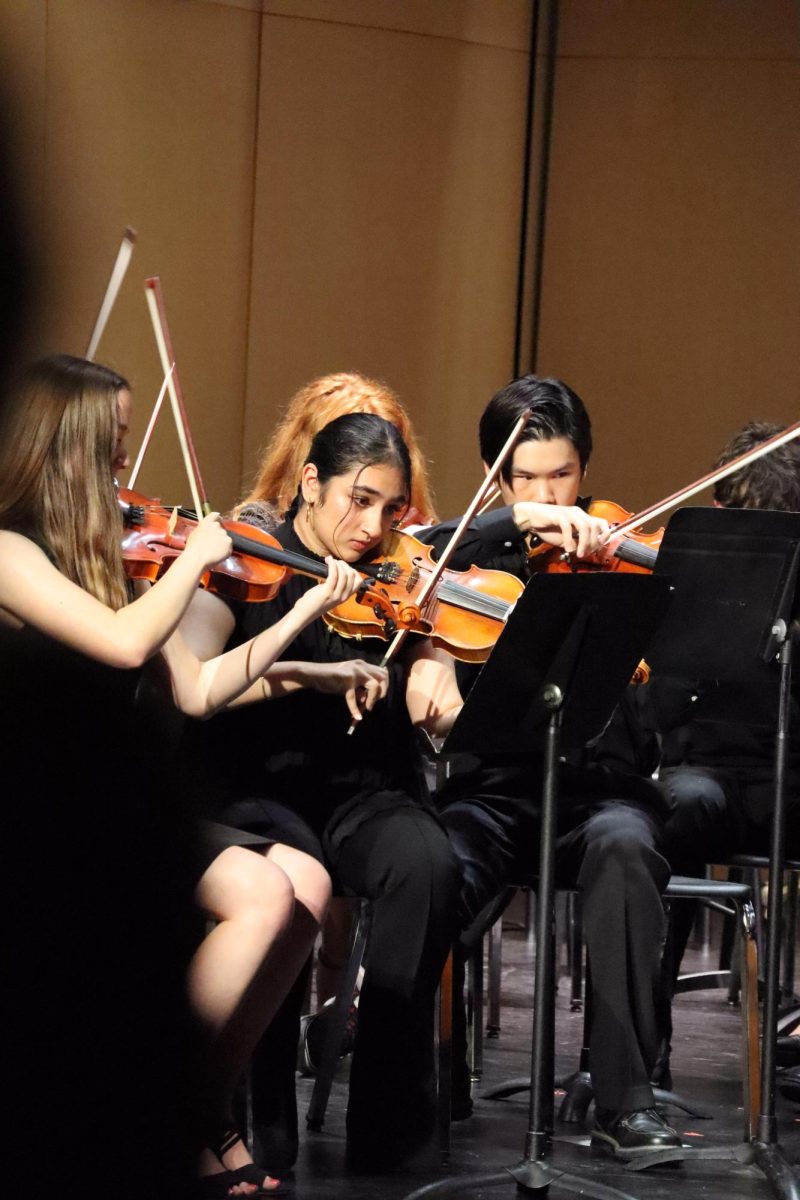 Meher Bacher center (11), and Ian Nguyen right (11) play violin at the orchestra concert on May 20.